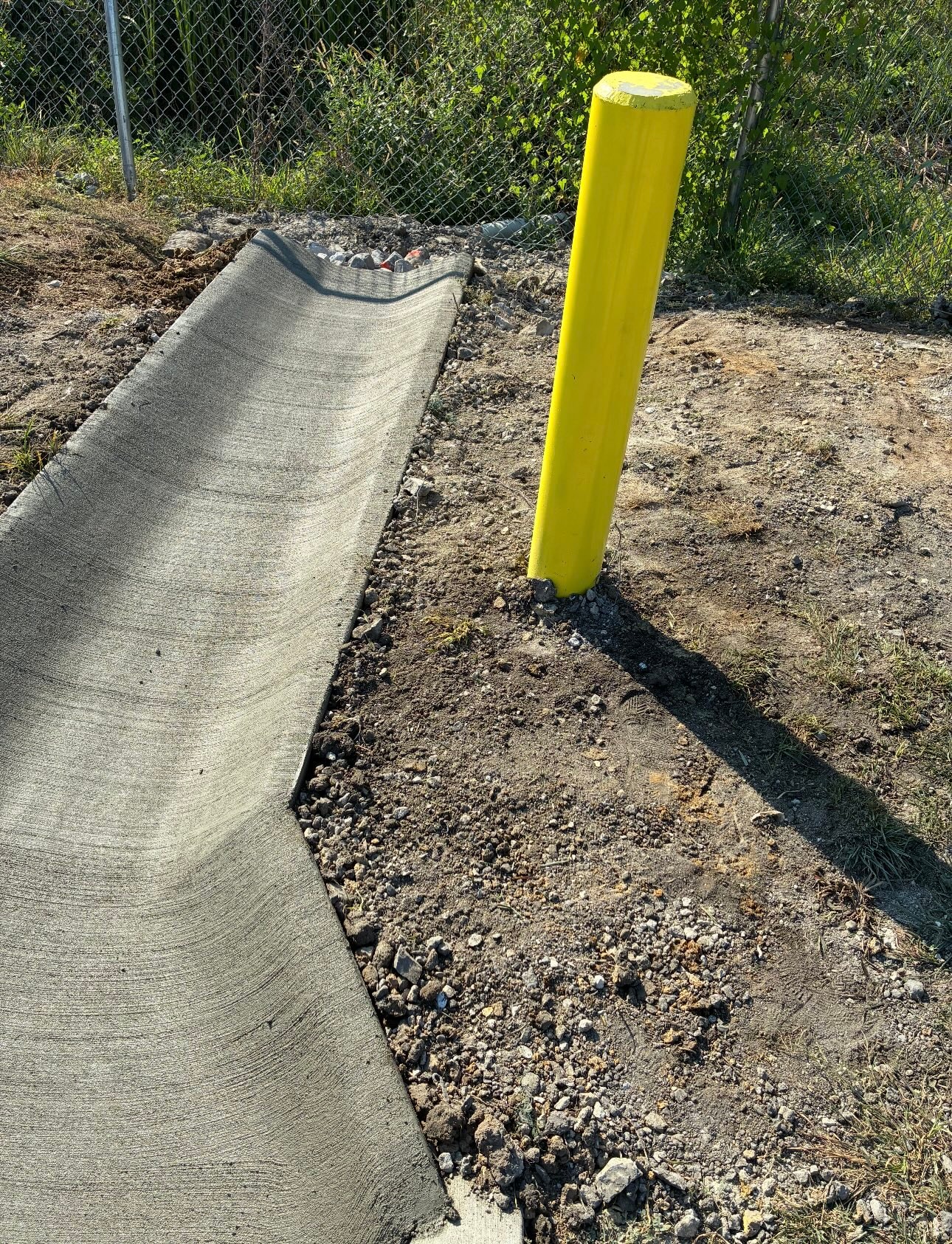 Yellow bollard and concrete curb installation